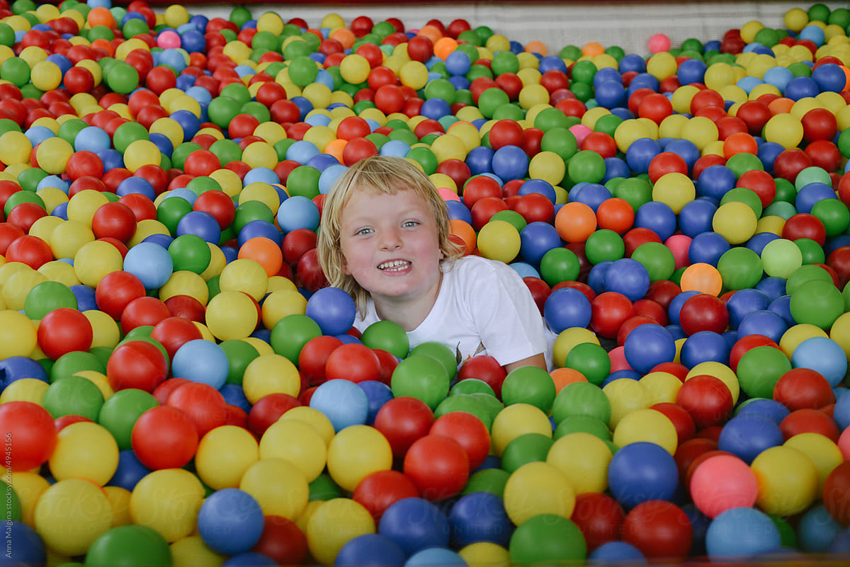 a happy kid playing in a ball pit