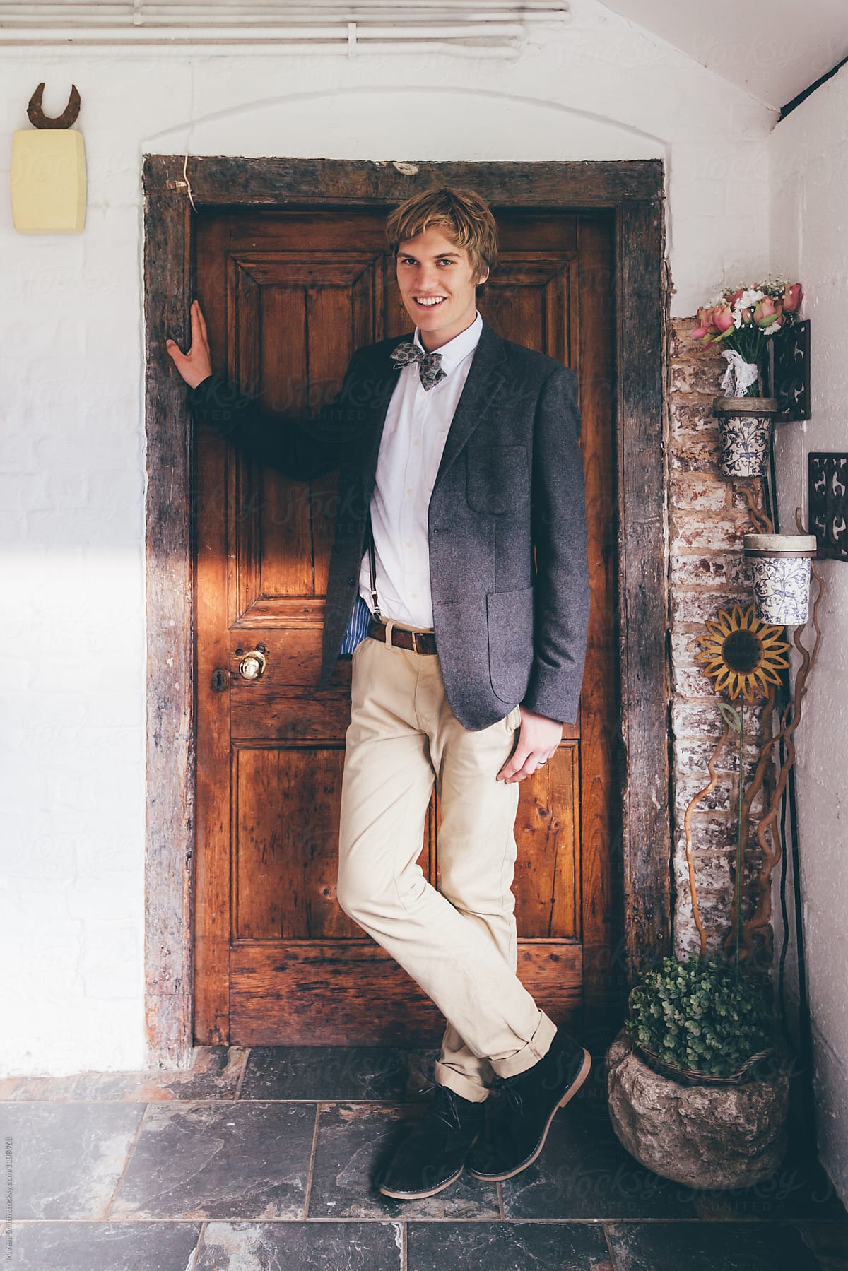 A real groom standing in the doorway  of a farmhouse on the day of his wedding