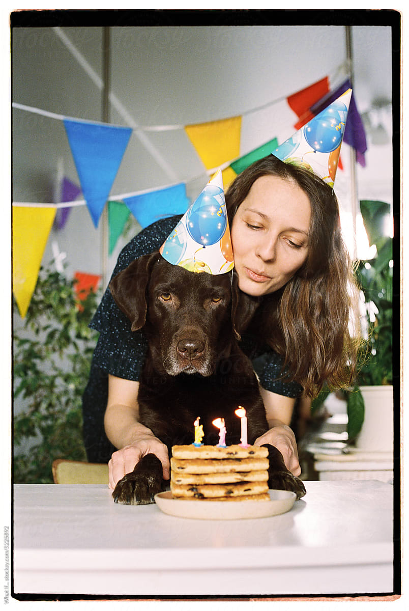Woman and her dog blow out the candles on a birthday cake.