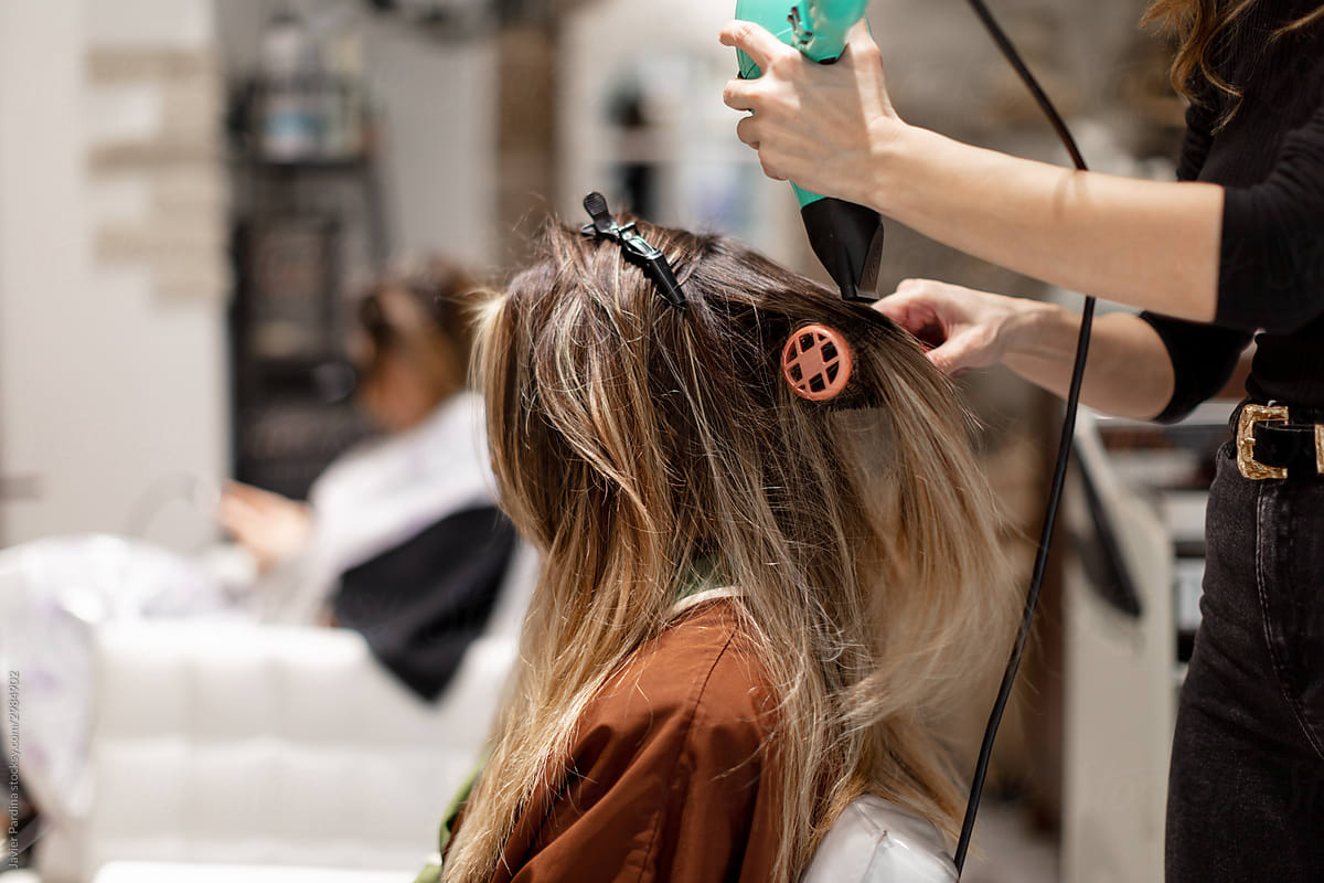 Hairdresser drying hair of woman