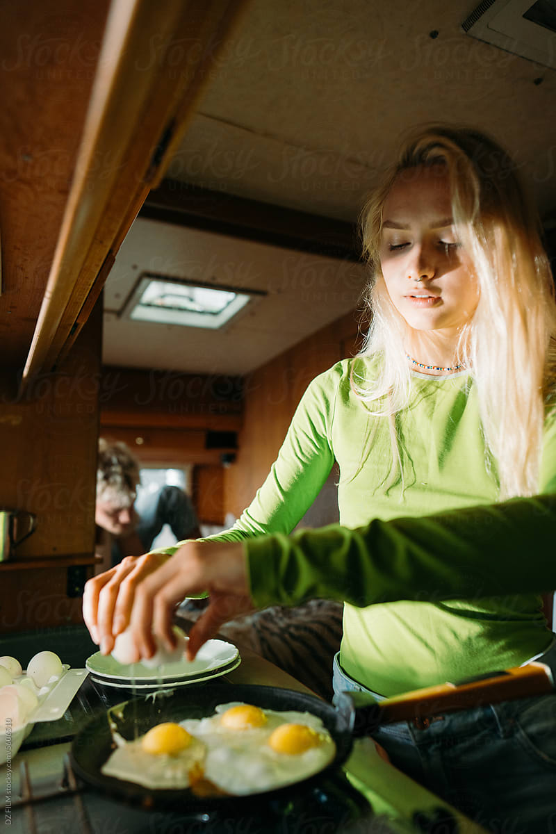 Woman frying eggs in van kitchen
