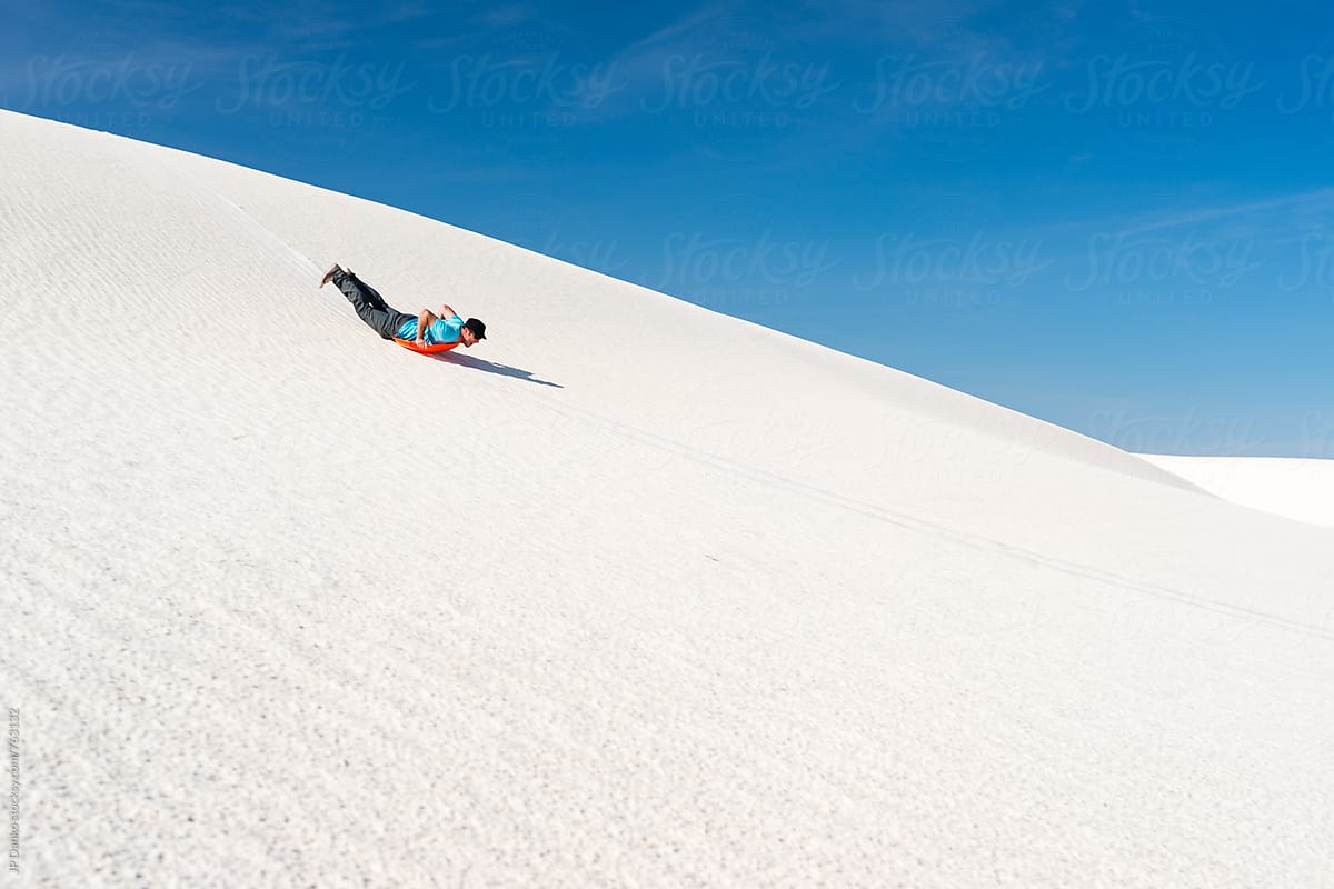 Man Sand Sledding on Sand Dune In White Sands National Monument New Mexico