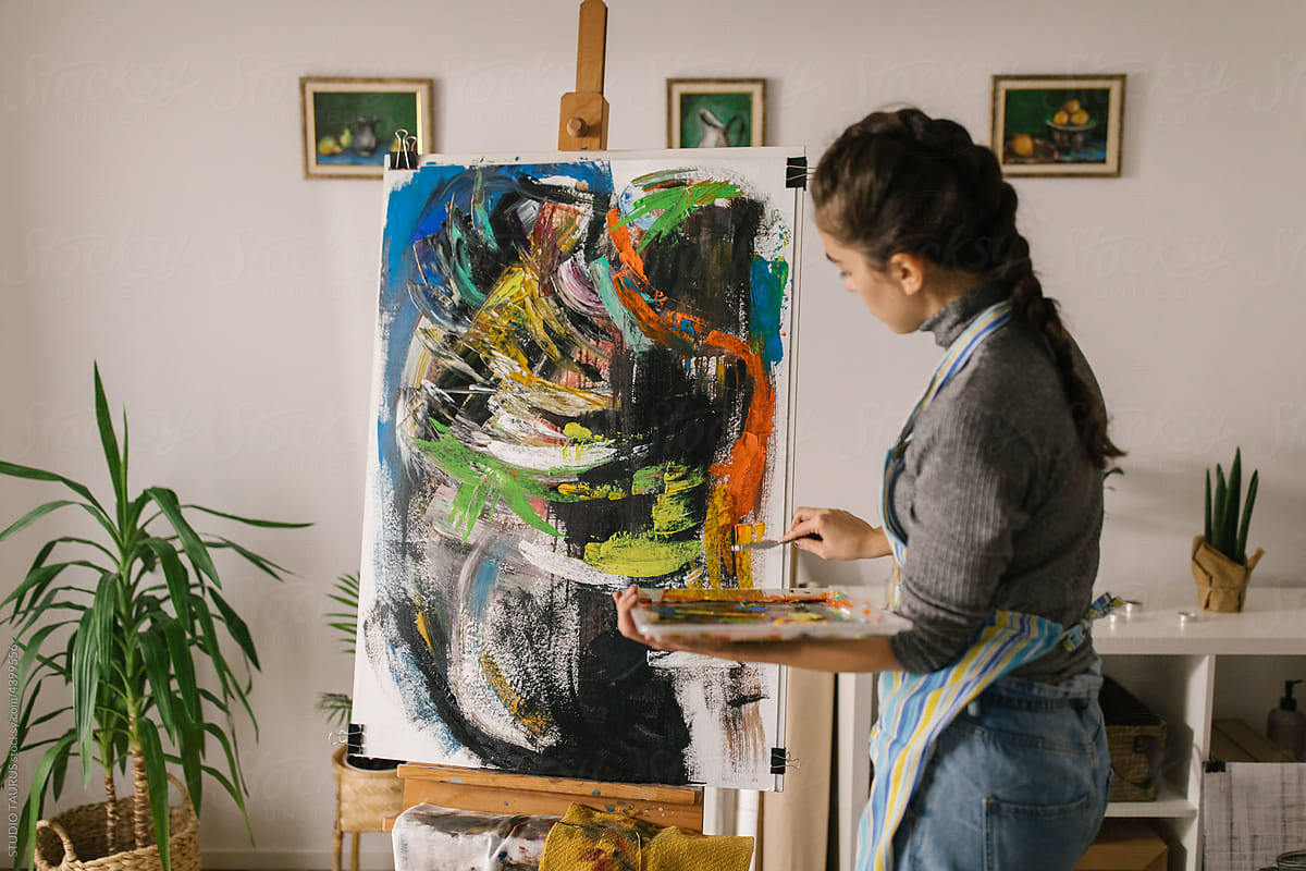 Female art student painting on canvas in home studio