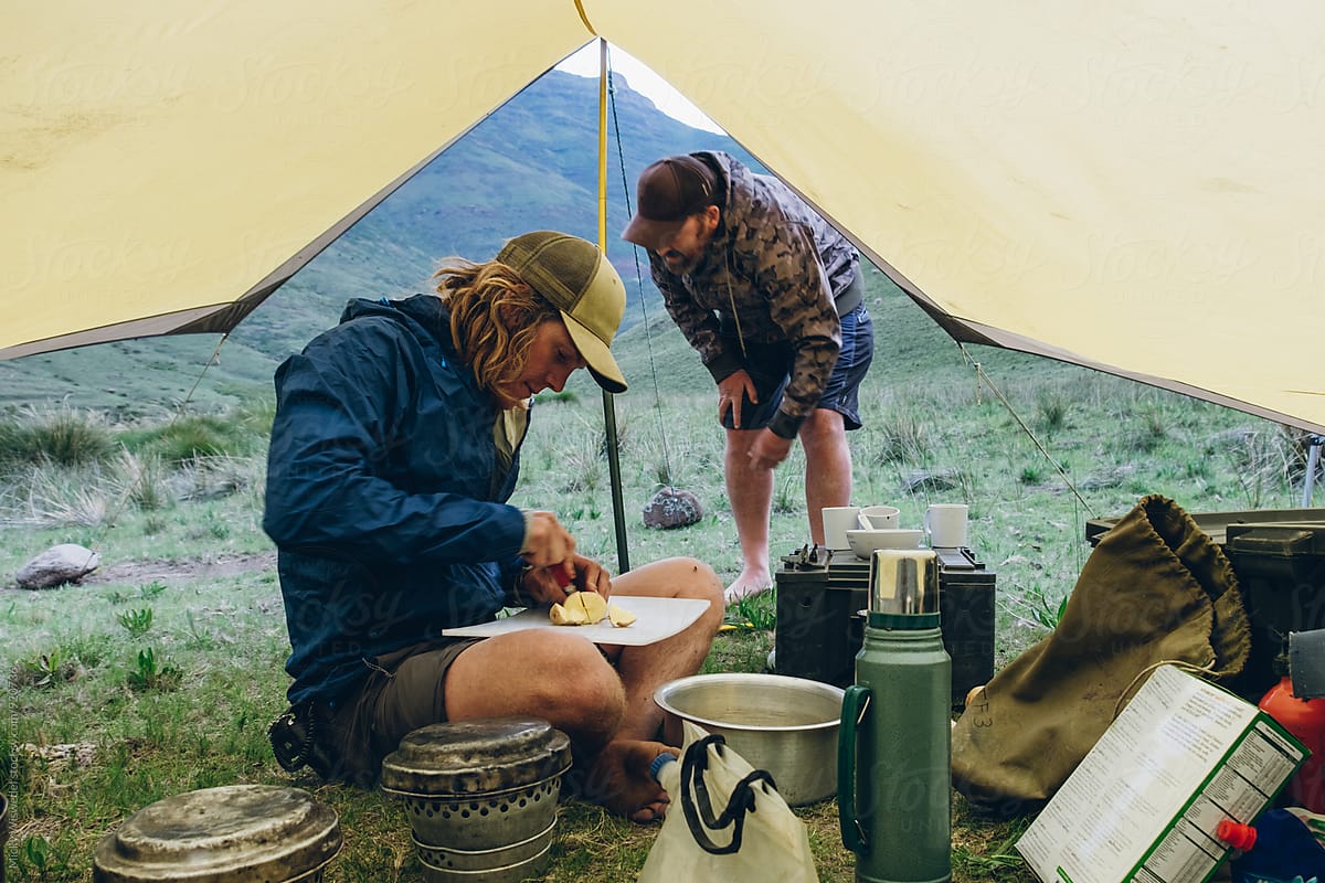hiker outdoorsmen preparing food in a tent shelter in the mountains