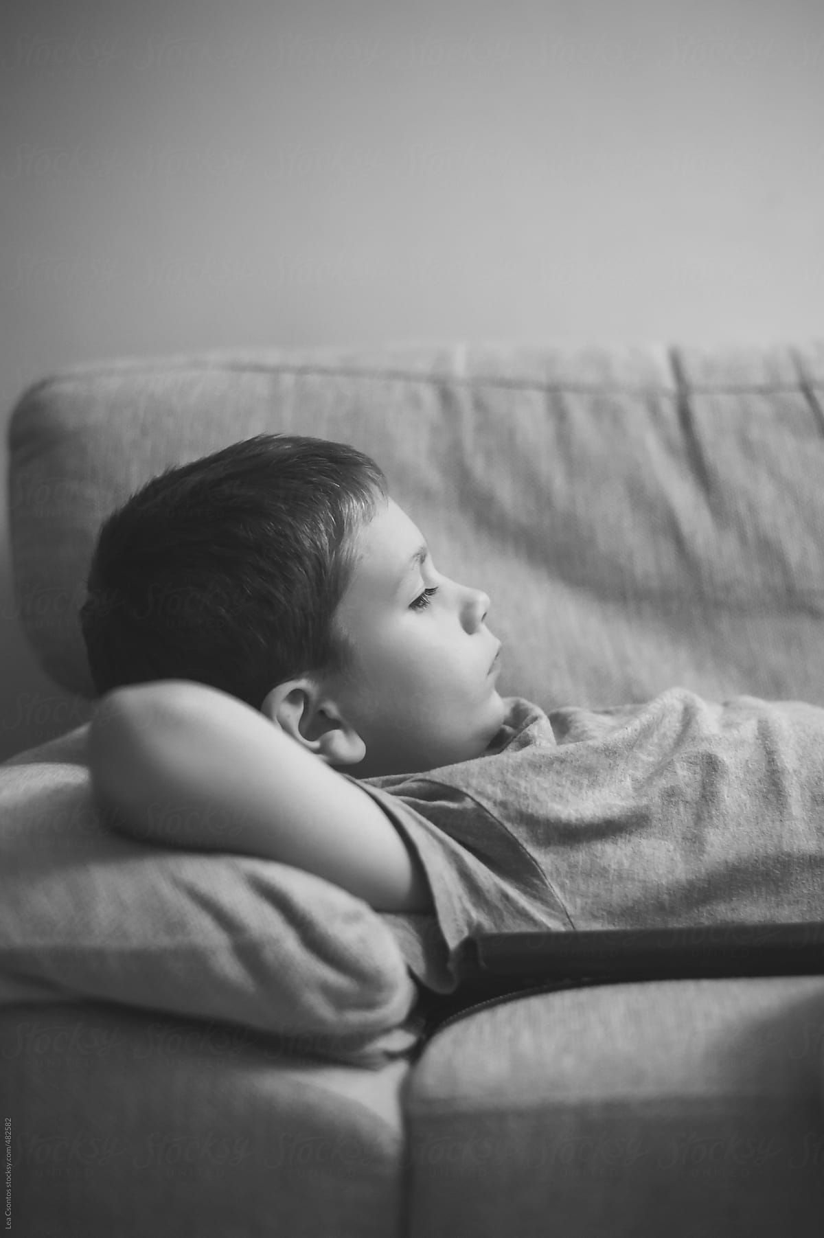 Young boy lying on a sofa in a relaxed manner with a serious face