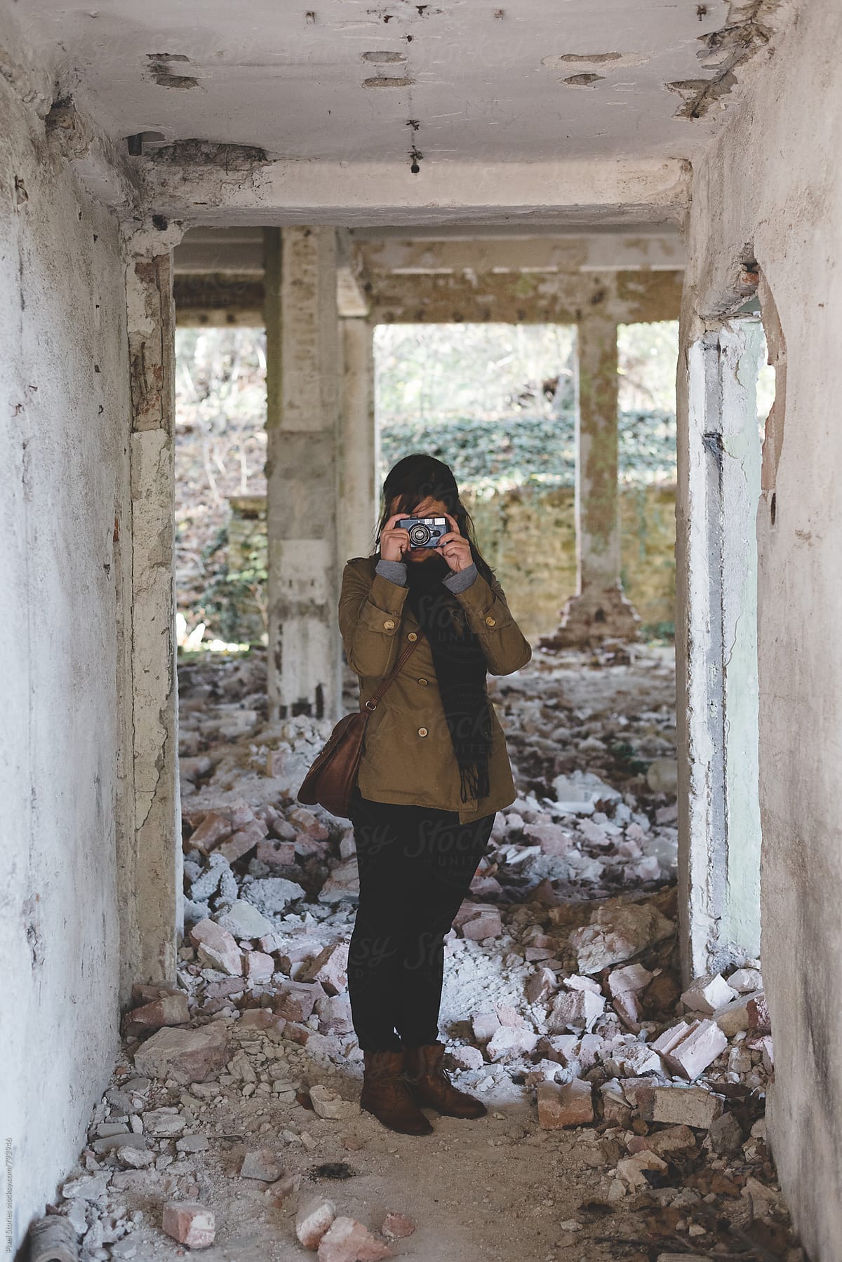 Young woman urban exploring an old building with her camera