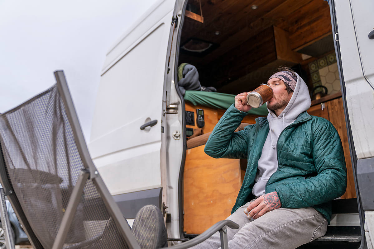 Portrait man drinking coffee in camper van in nature