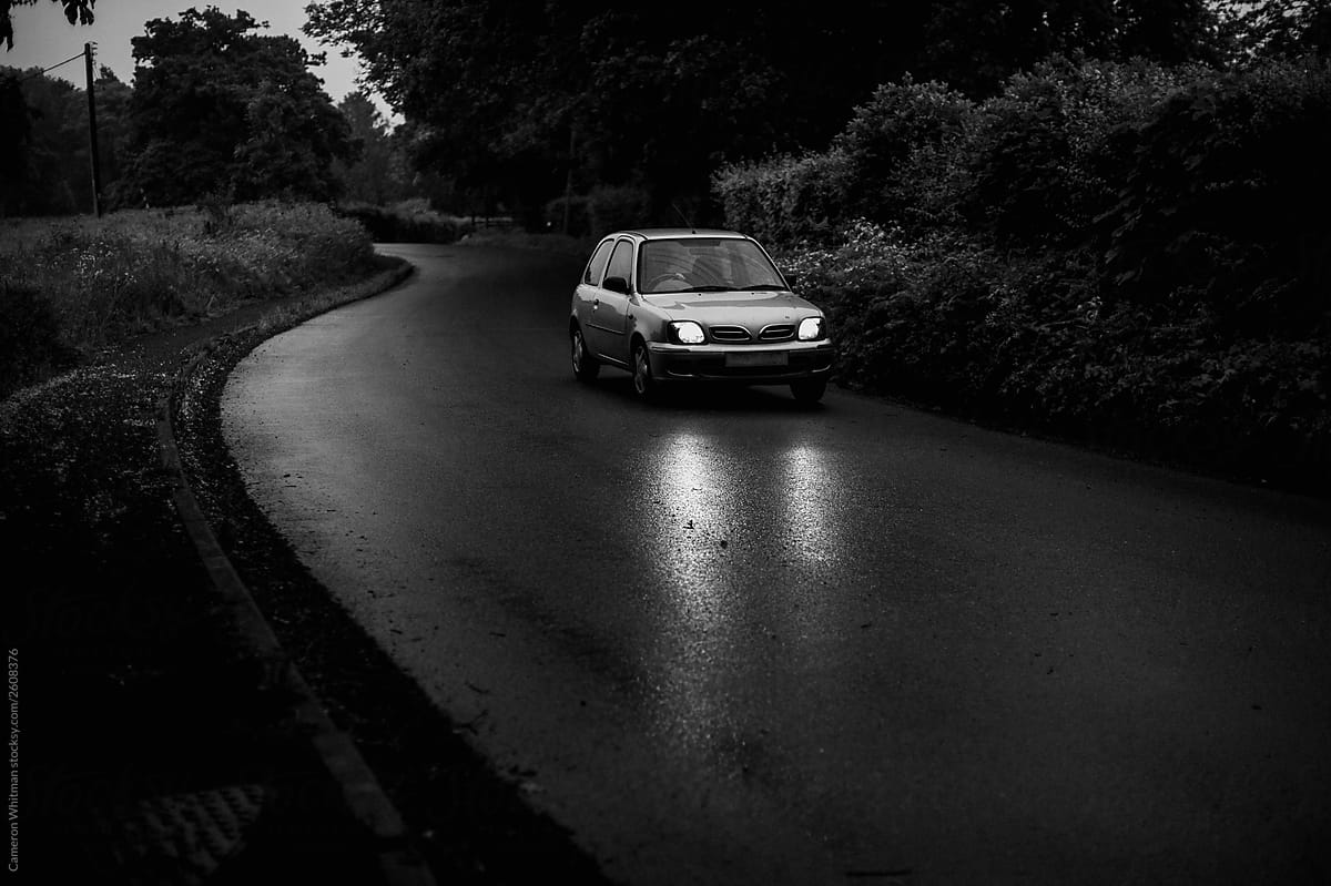 Car on wet winding road black and white