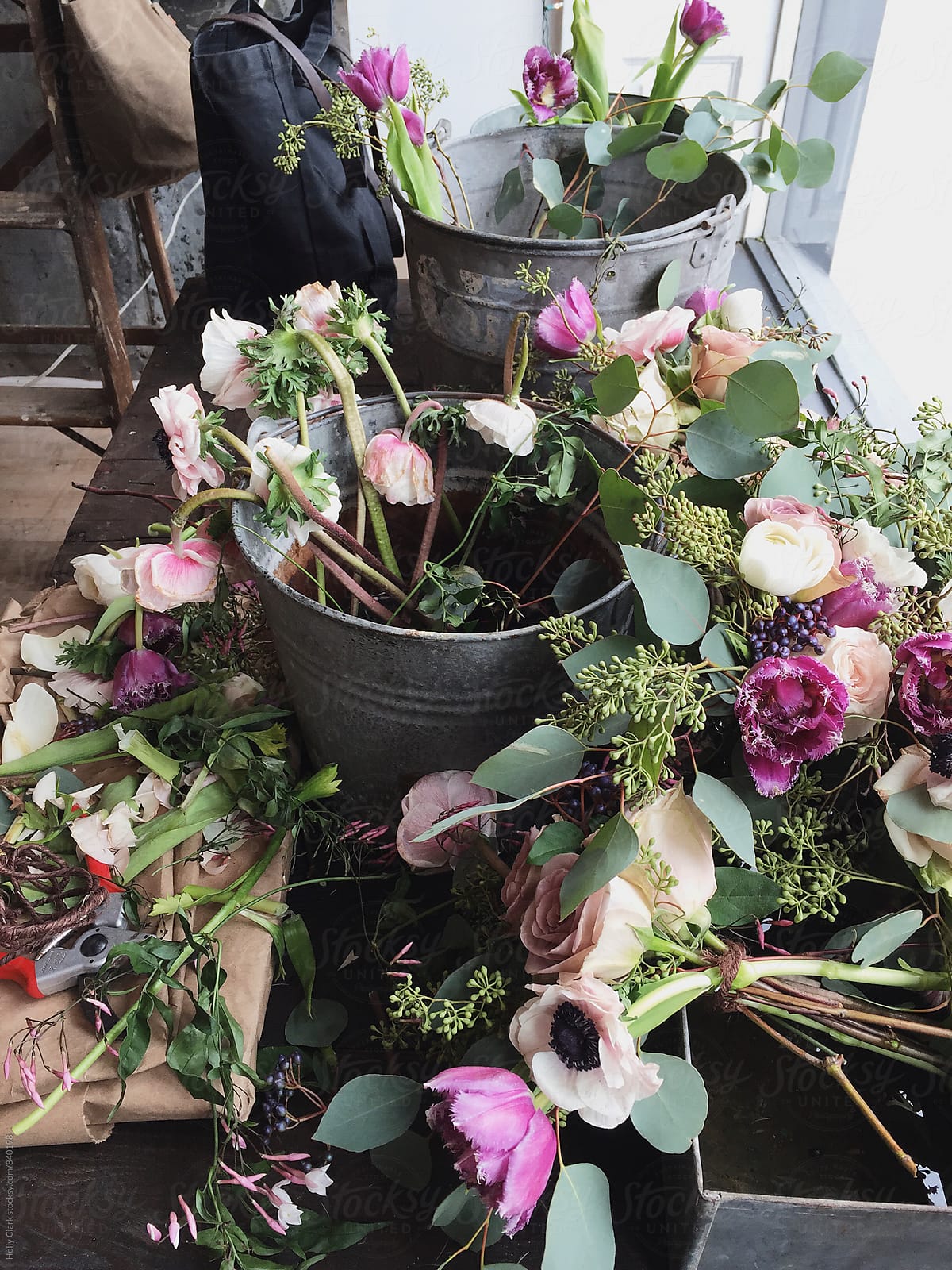 Galvanized steel buckets of flowers rest on a table for arrangements