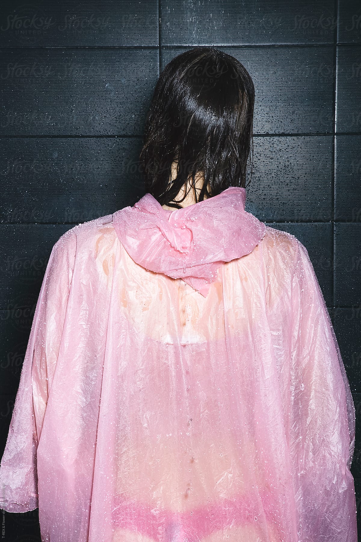 Back view of woman in pink raincoat taking a shower