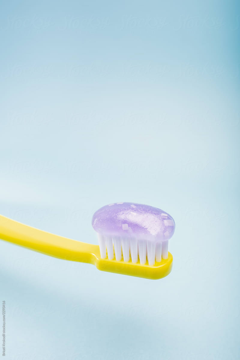Yellow Toothbrush With Toothpaste On Blue Background Close Up