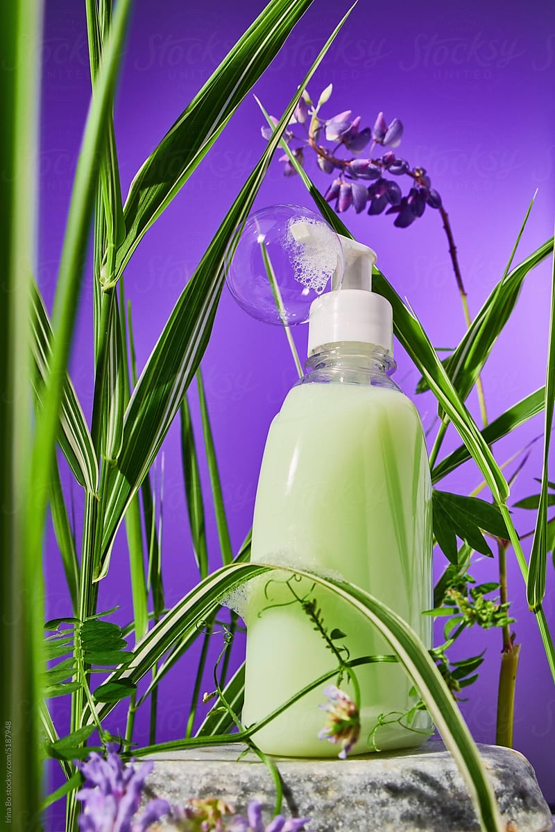 A bottle of liquid green soap stands in the grass