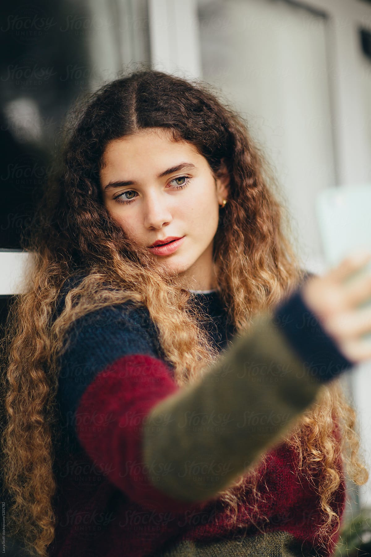 Beautiful young woman acts seductively while holding her phone in front of her for a selfie