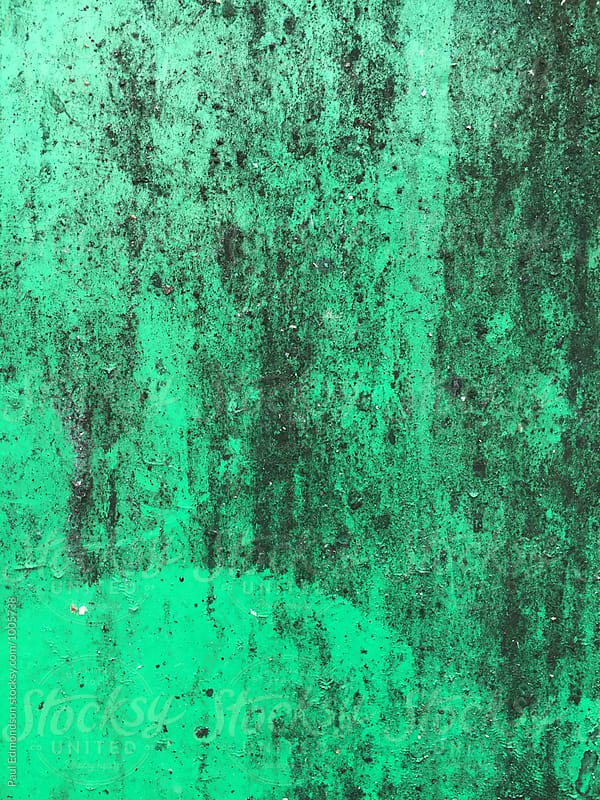 Close up of green peeling paint and graffiti on metal wall