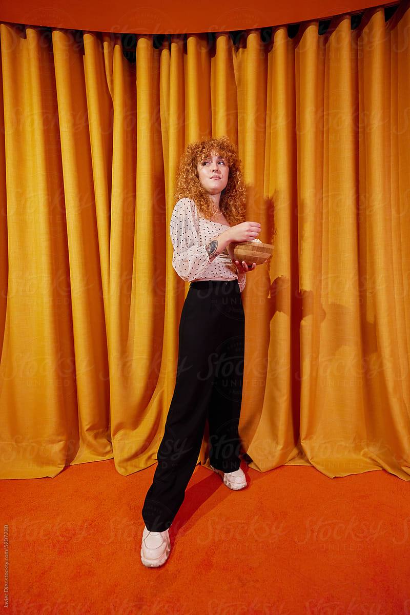Young woman with popcorn near curtain