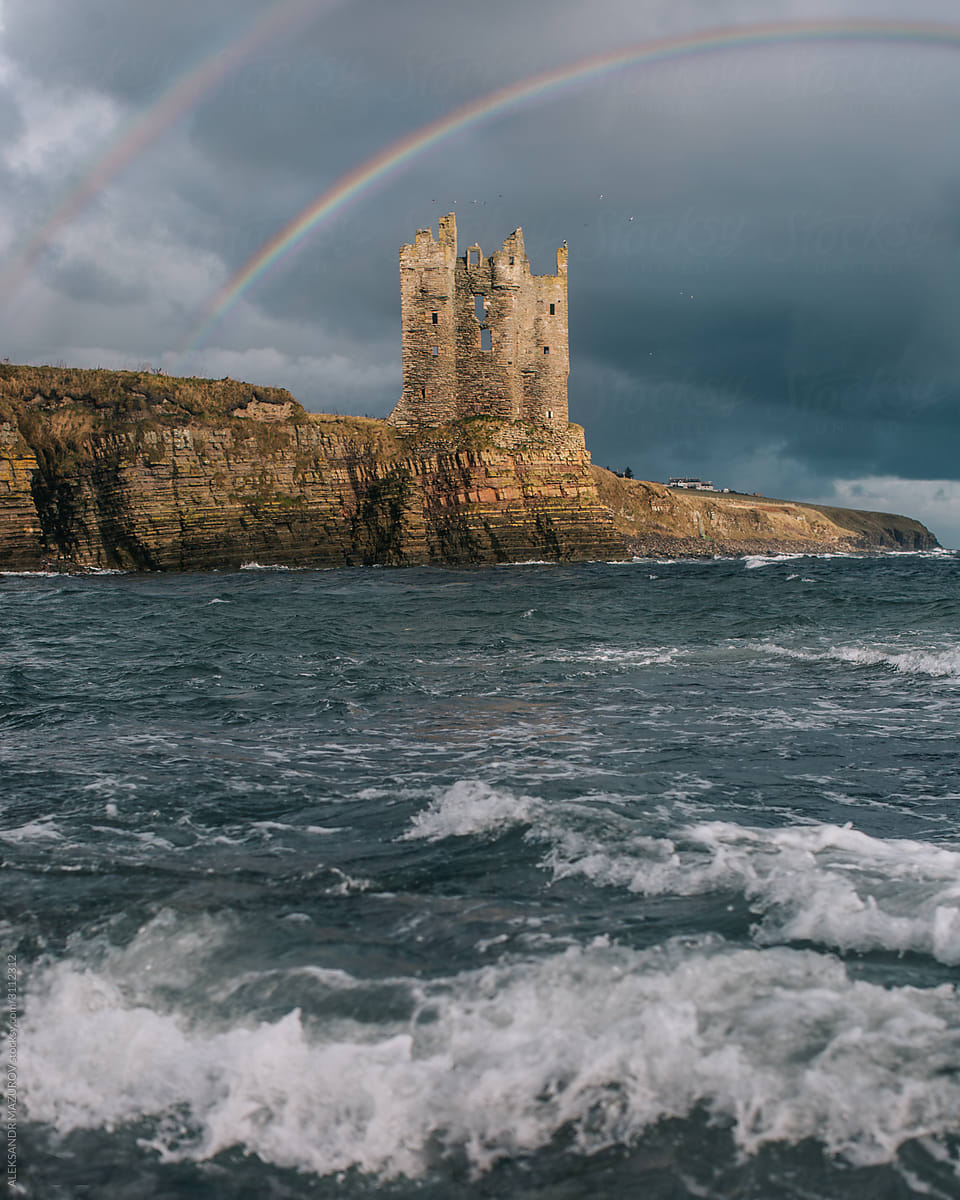 Double rainbow over the castle ruins on the shore