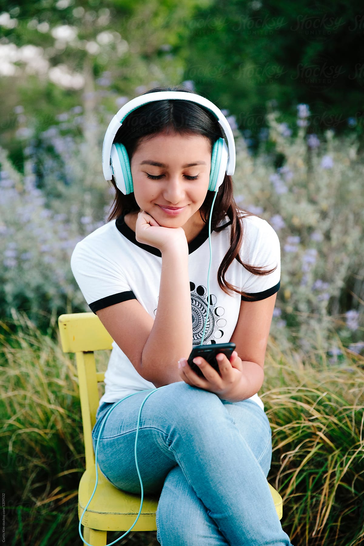 Pretty teenage girl wearing headset and holding mobile phone