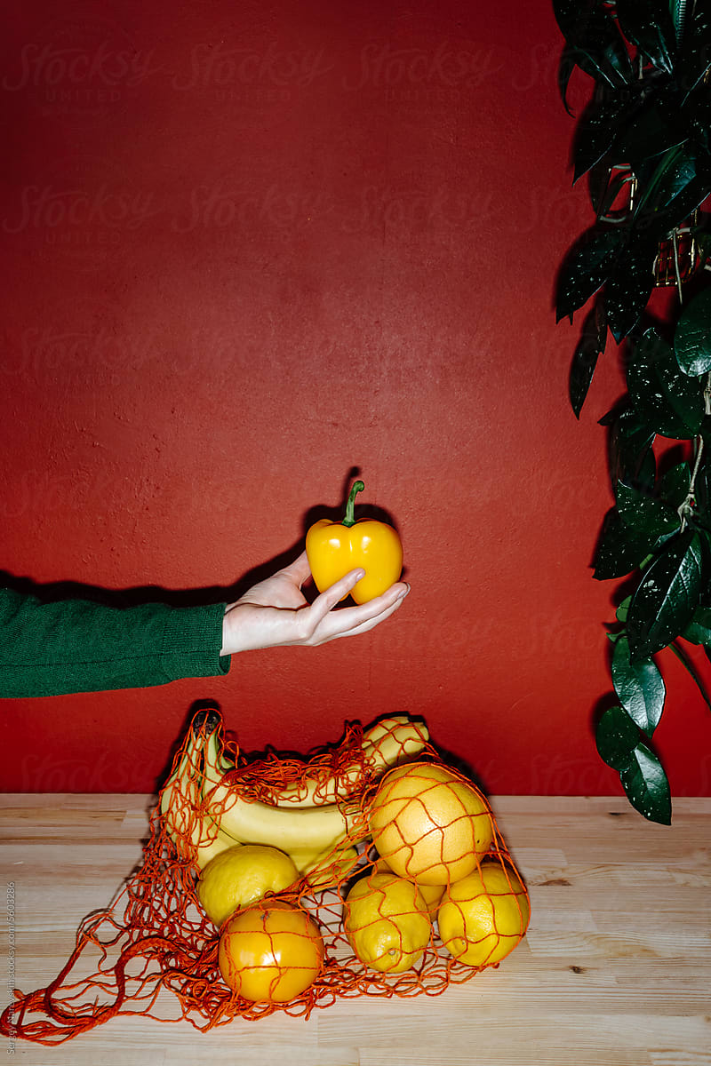 Anonymous person with pepper near bag with yellow groceries