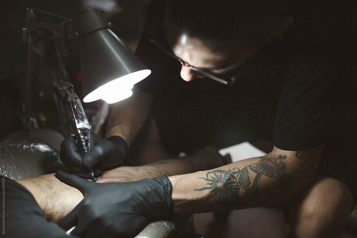Man Tattoo Artist drawing a tattoo on a man\'s arm
