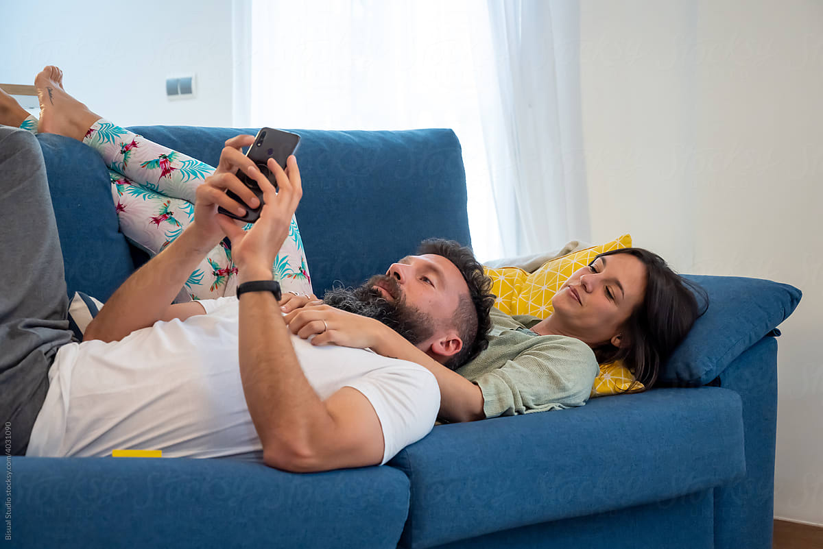Couple with smartphone resting on sofa together