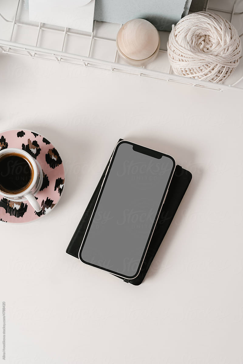 Smartphone with planner and coffee cup placed on desk