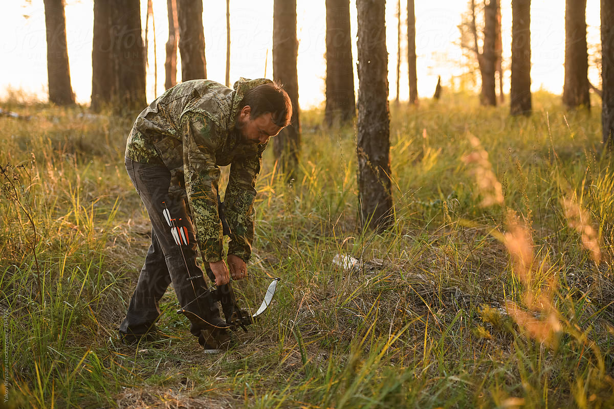 Adult man hunting with a recurved crossbow in the forest on an autumn day.