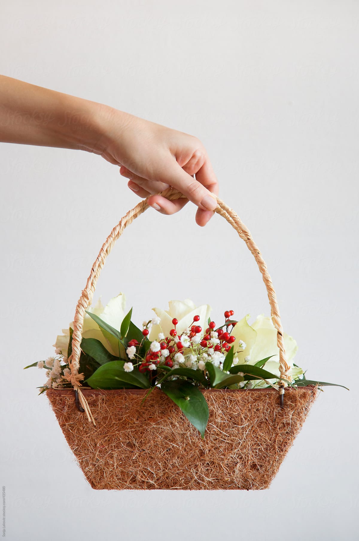 hand holding a basket with flower arrangement