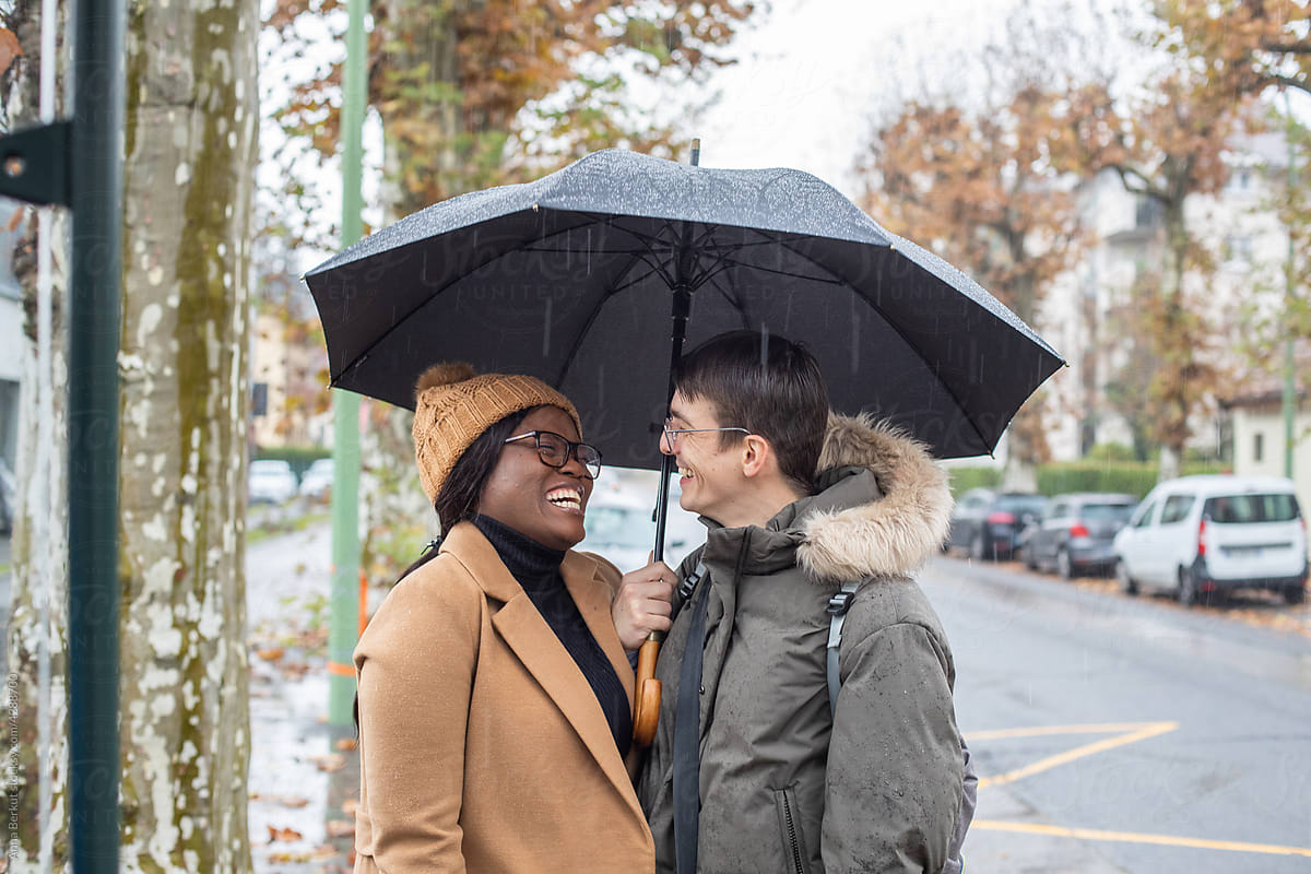 couple portrait laughing under umbrella in the rain
