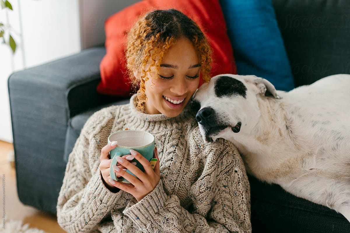 Teenager at home relaxing with dog while drinking tea