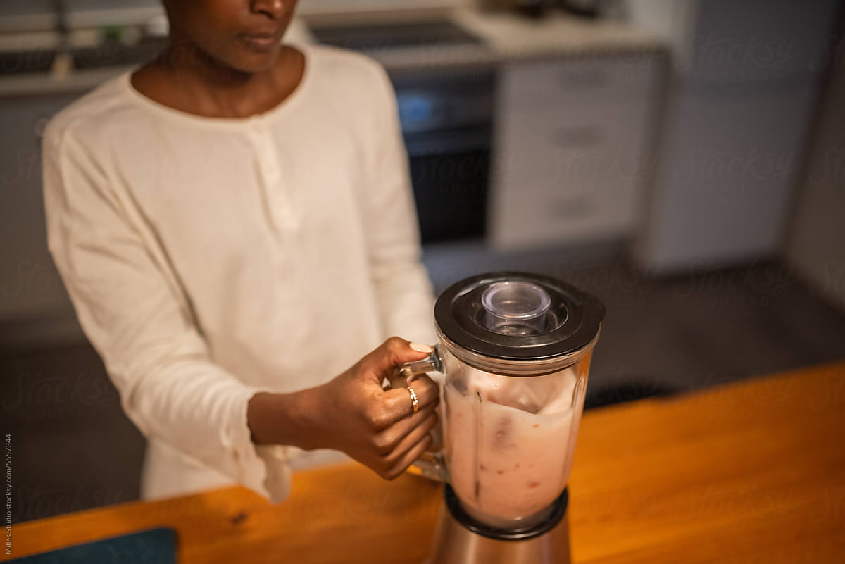 Crop black woman mixing milkshake with blender