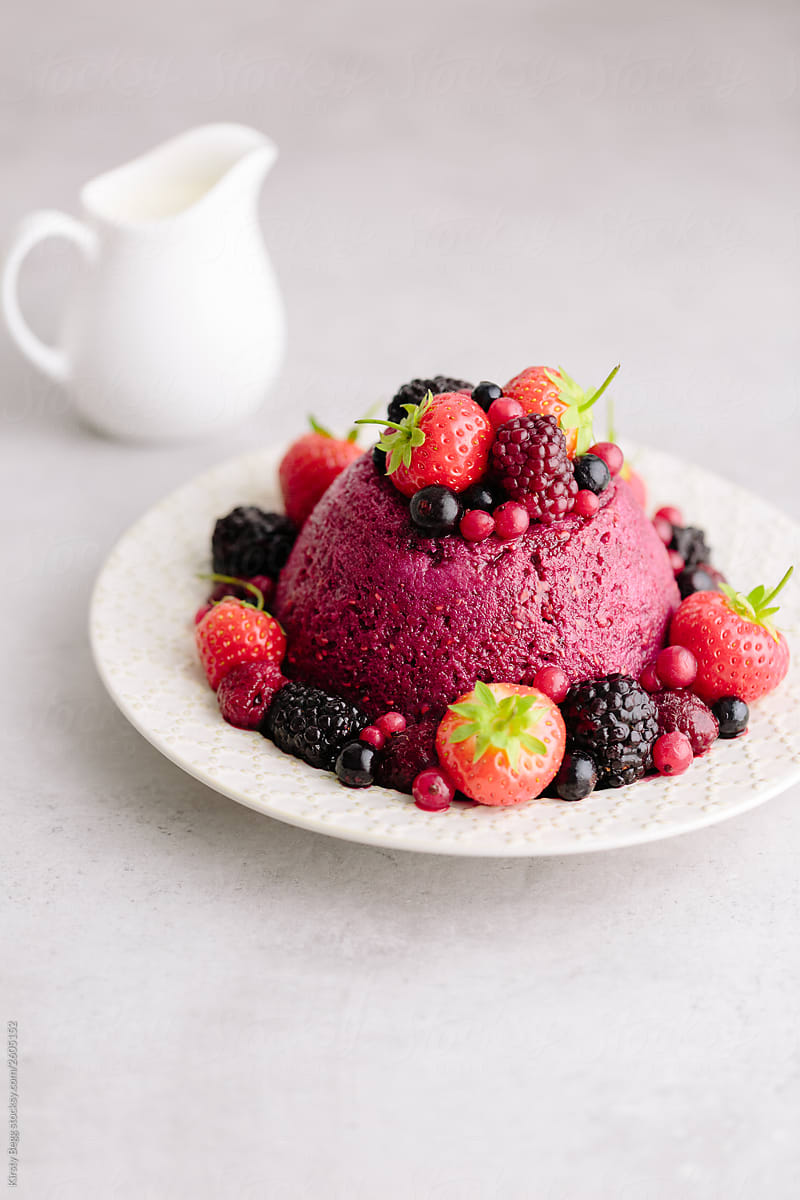 English Summer Pudding on plate with cream behind