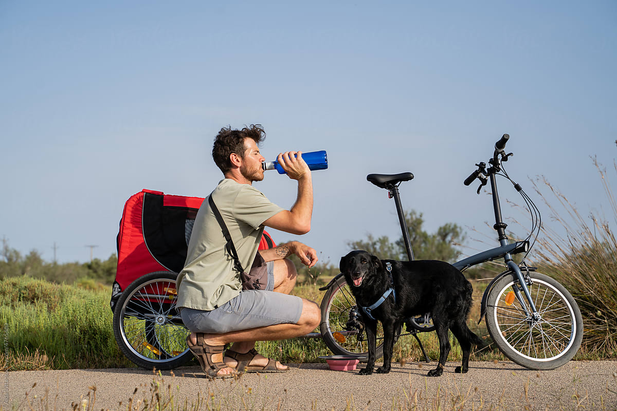 Man drinking water with dog in nature