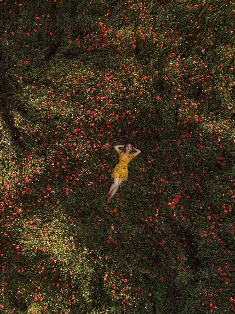 Woman lying on green field with flowers