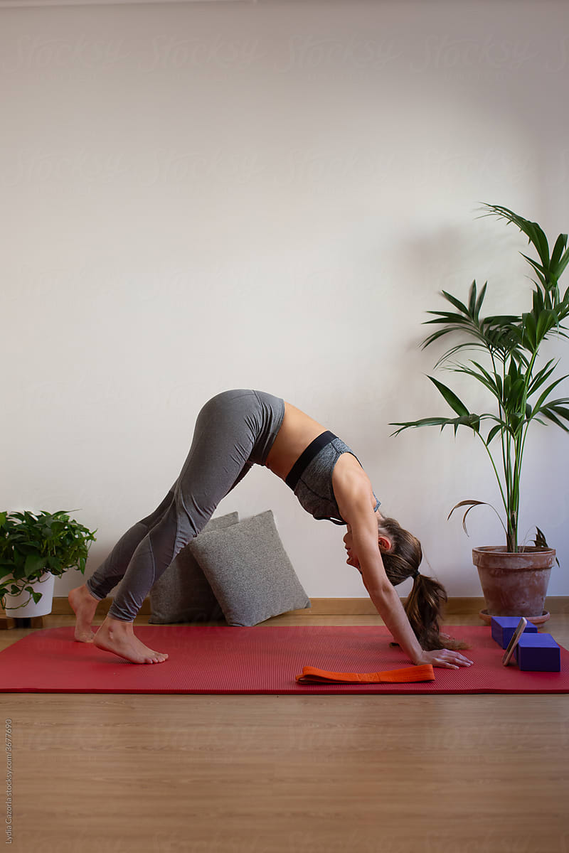 Young woman practicing yoga online is her apartment