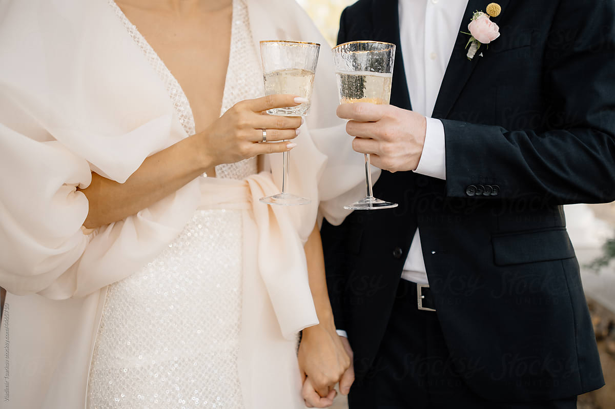 bride and groom holding hands and drink champagne