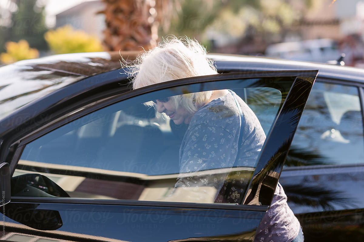 Senior woman opening car door at street