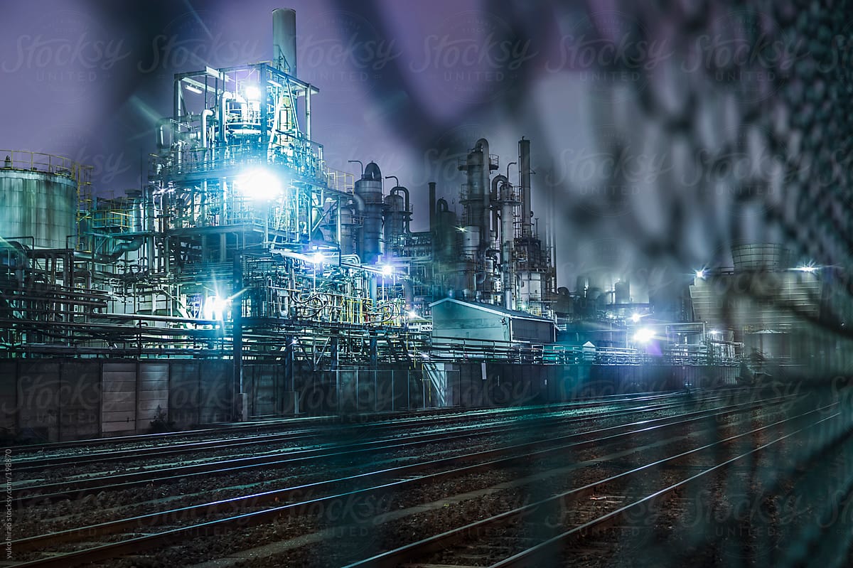 Chemical factories and railroad behind fence at night