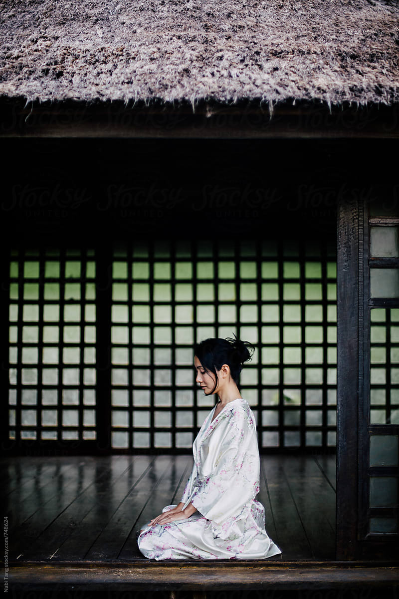 Beautiful Japanese woman in casual silky kimono sitting in traditional Japanese house