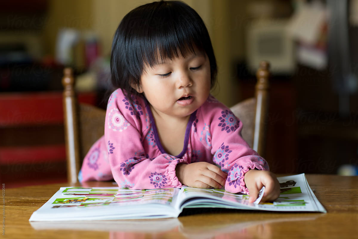 Girl playing with a sticker book at a dining room table