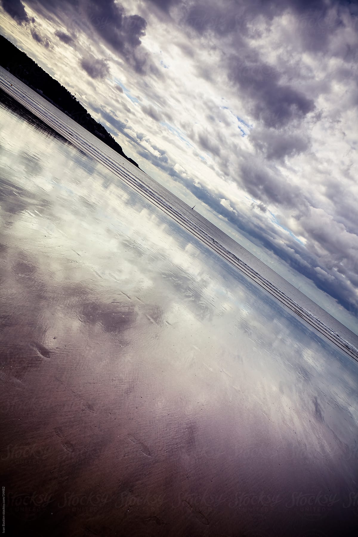Reflection of the cloudy sky in a beach at low tide