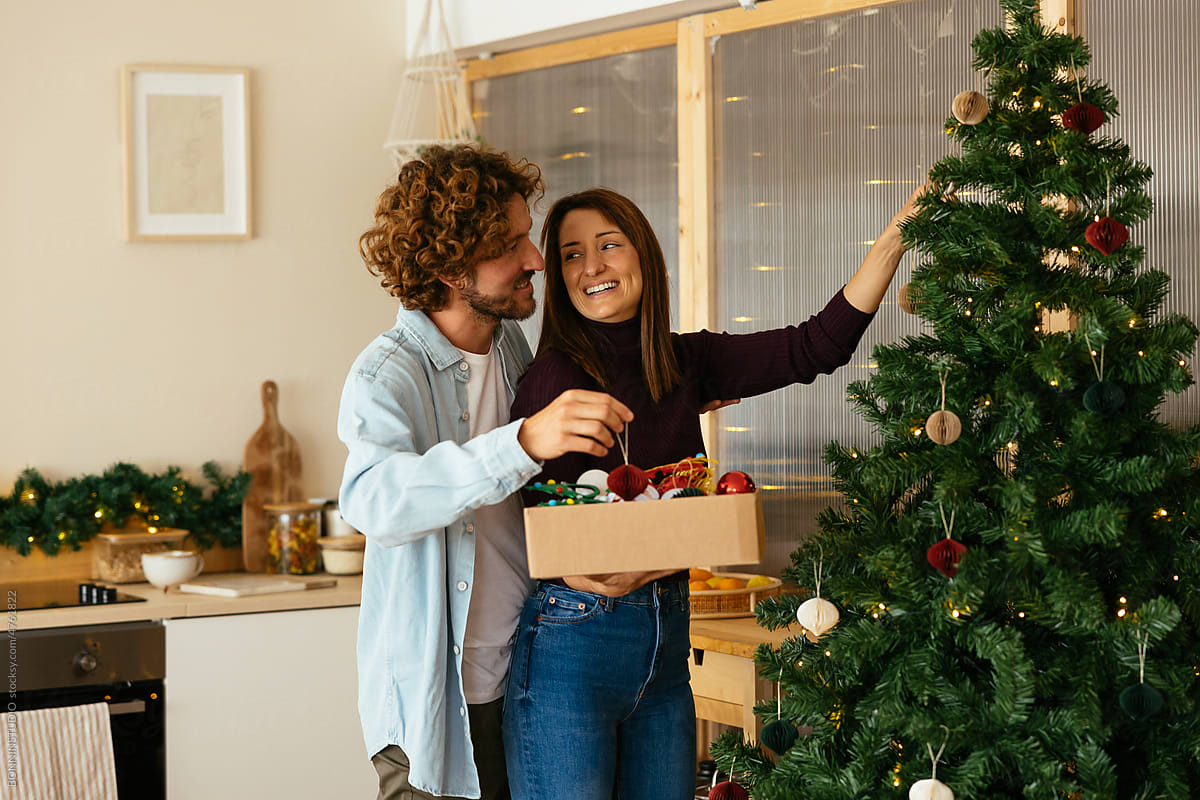 Boyfriend helping girlfriend to decorate Christmas tree