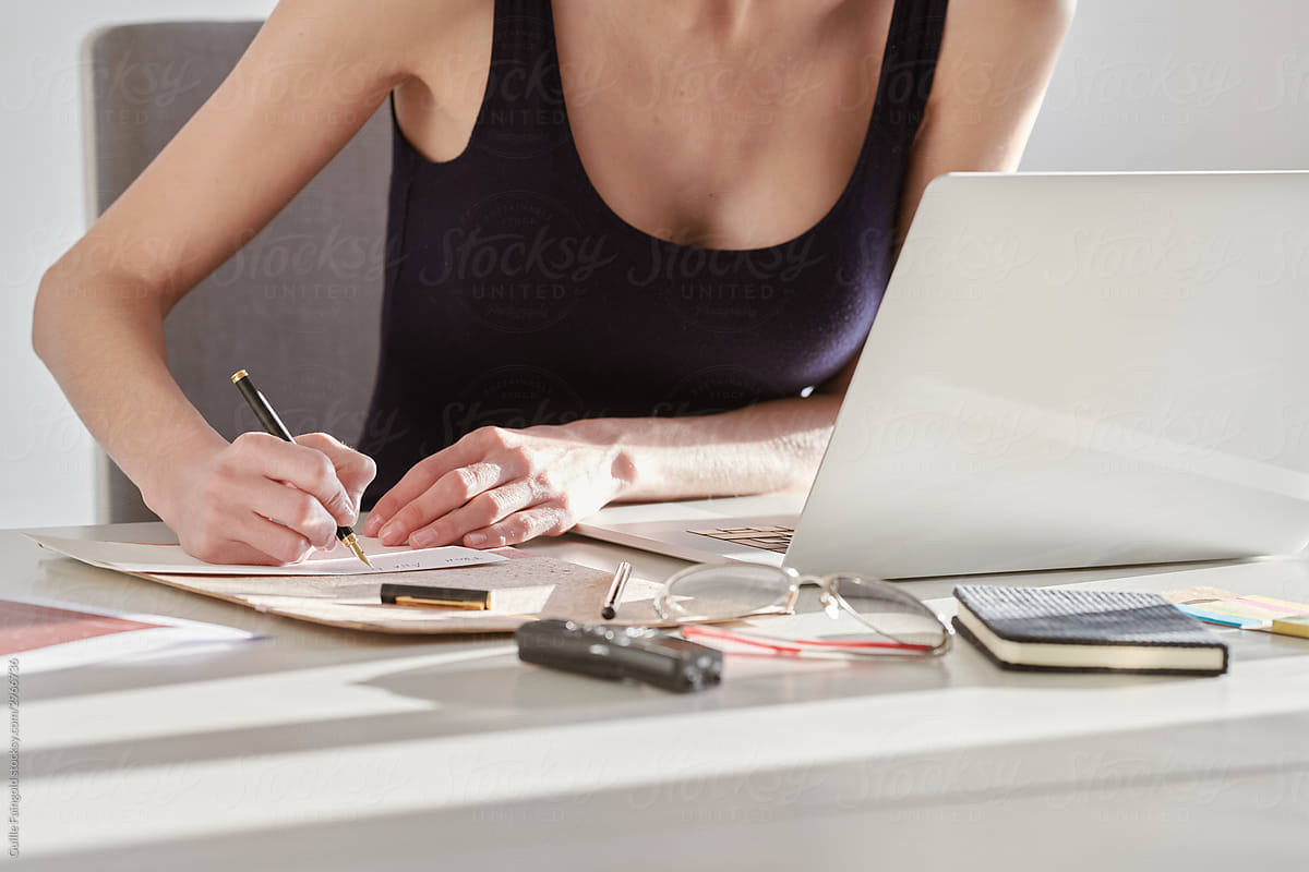 Woman filling documents while working at laptop