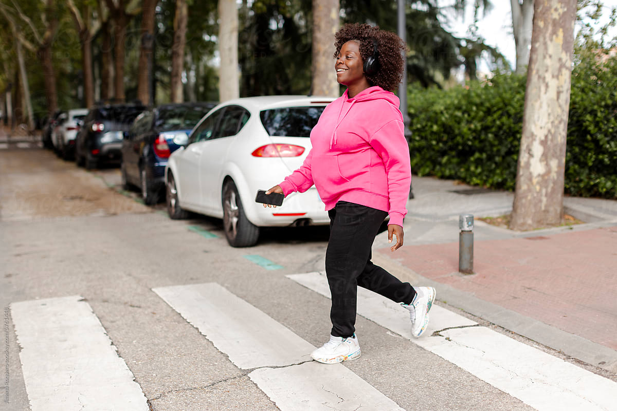 Smiling Pregnant woman in sportswear on the street with headphones