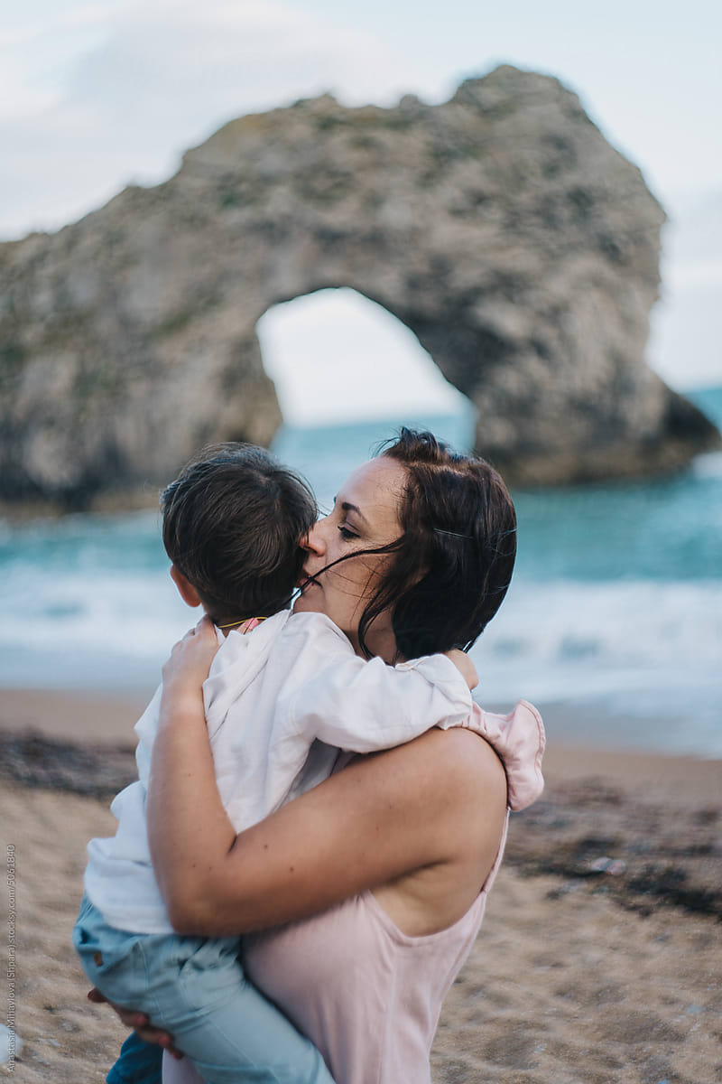Mother Kiss Her Son Near Ocean and Rocks in summer