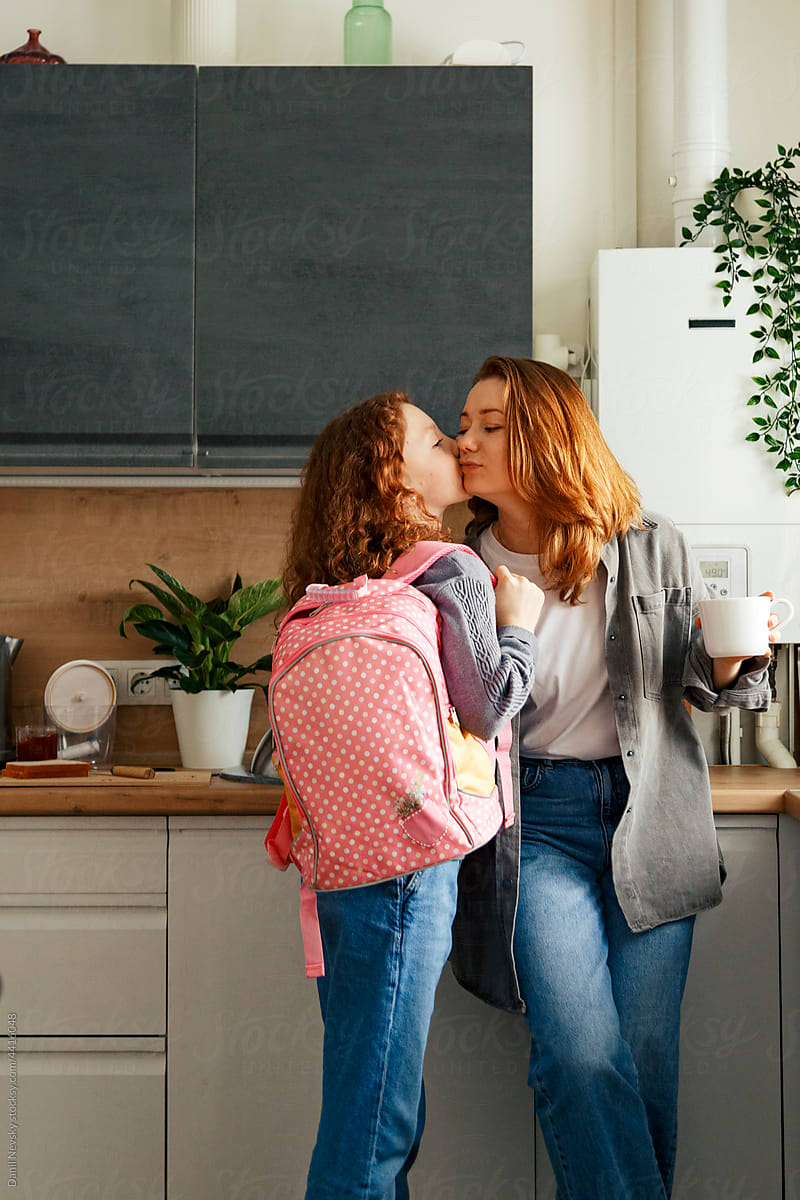 Schoolgirl kissing mother at home