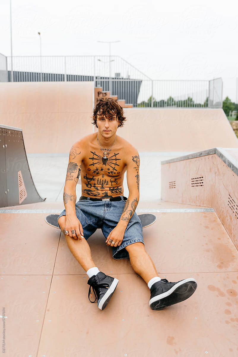 Portrait of a man with tattoos on a skateboard