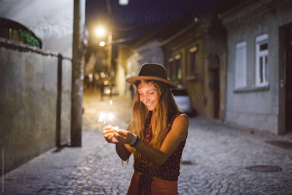 Joyful Young Woman Standing On The Street With Sparklers