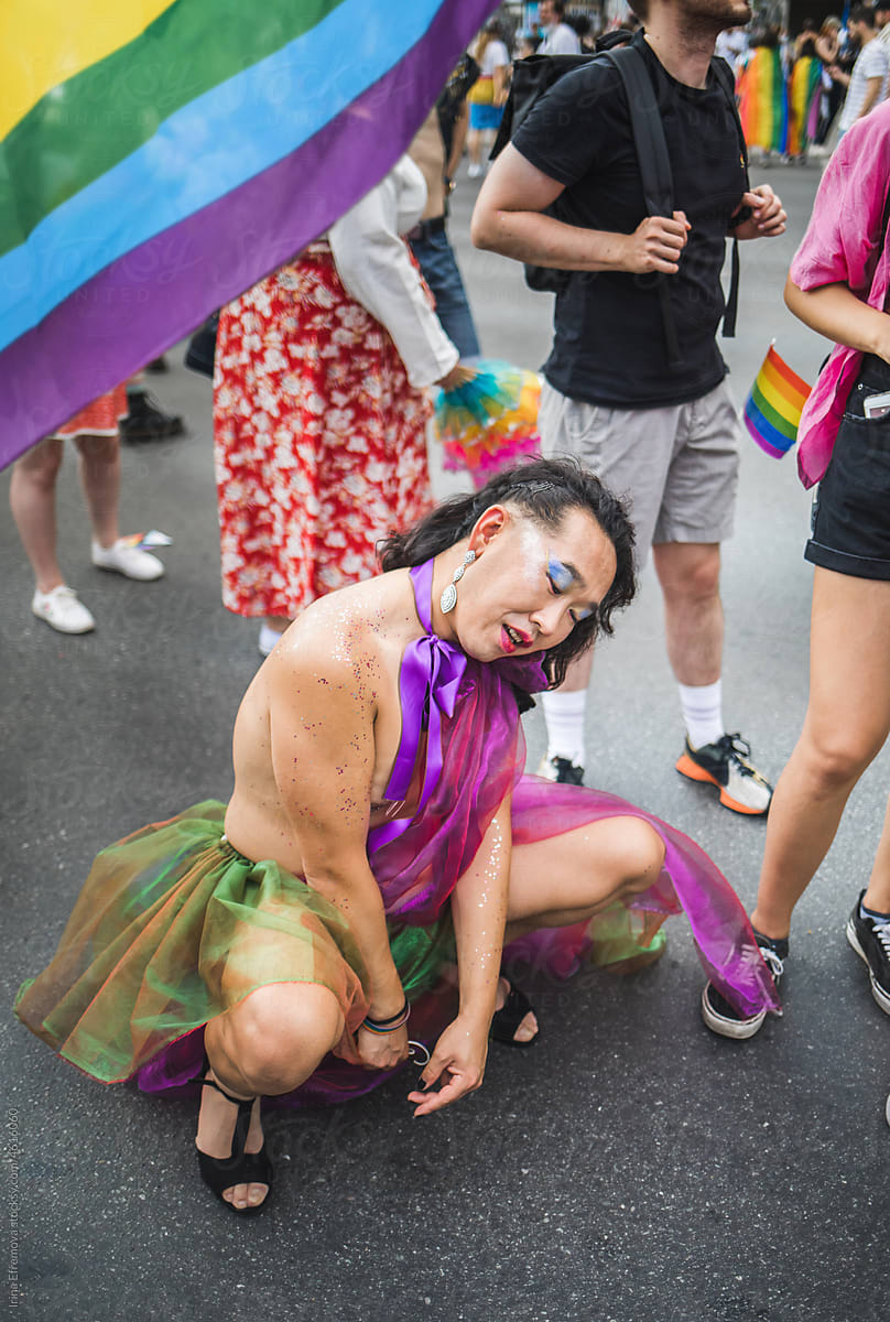 Cute asian man in a rainbow coloured chiffon dress posing on a floor