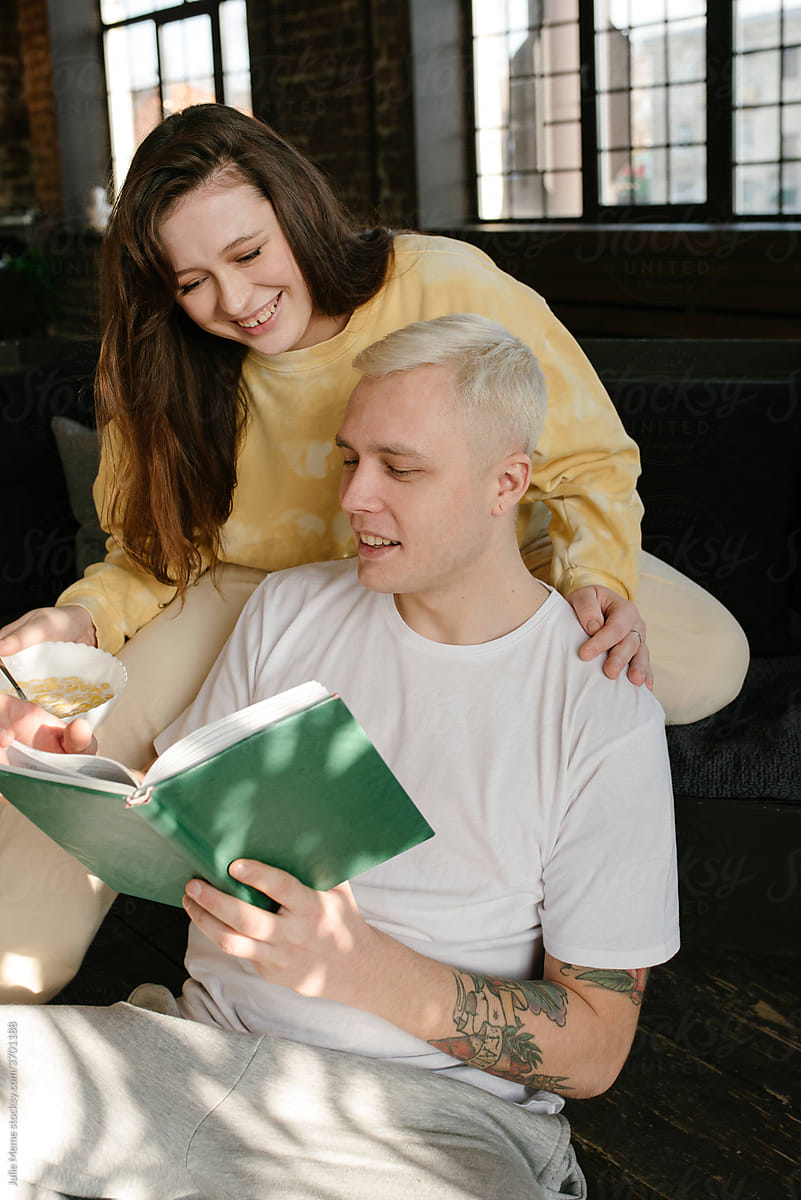 Cozy couple reads a book on the sofa