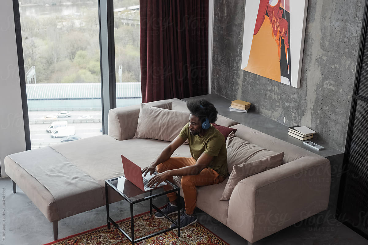Black freelancer using laptop in modern apartment